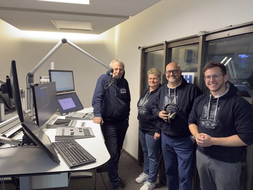 RSH-Moderator Carsten Kock und drei Personen mit Walter-Fiedler-Hoodie stehen in einem Radiostudio