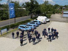 Die Mitarbeitenden von Walter Fiedler stehen auf dem Parkplatz in Form der Zahl 100